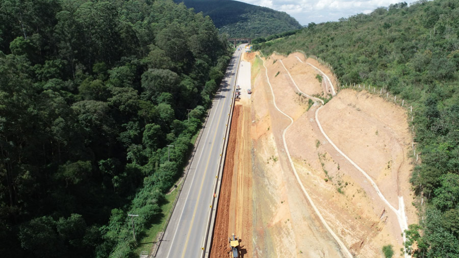 Perspectiva aérea da construção de uma estrada, com obras e a infraestrutura em desenvolvimento as margens da rodovia.